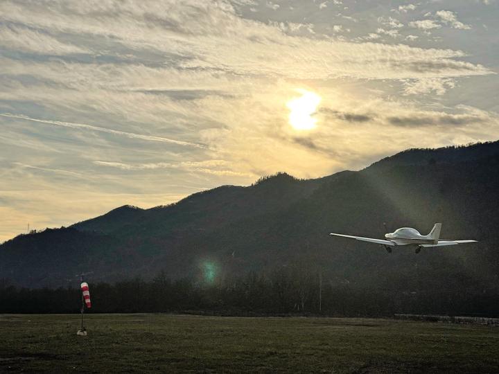 Un ultraleggero Dynamic in decollo al tramonto con le montagne in controluce
