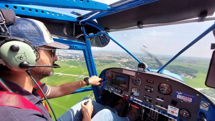 Pilota ai comandi del Savannah I-D555 in volo sopra la pianura e i campi coltivati