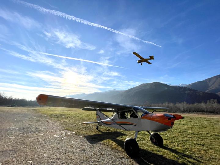 Un ultraleggero in volo sopra il campo mentre un altro aereo attende a terra